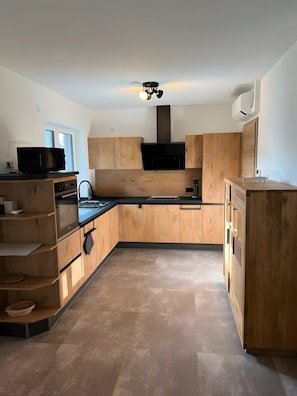 A modern kitchen with wooden cabinetry, a built-in oven, and a ceiling fan.