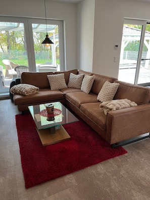 A modern living room with a sectional sofa, a glass coffee table, and a red rug.