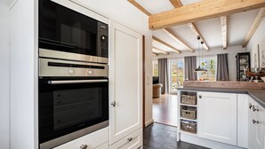Une cuisine dotée de fours encastrés, de meubles blancs et d’un plafond en bois.