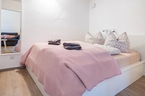 A bedroom with a bed, pillows, a blanket, and a bedside table. - Holiday Apartment 'LeeKee' with Lake View, Balcony and Wi-Fi (Wunstorf)