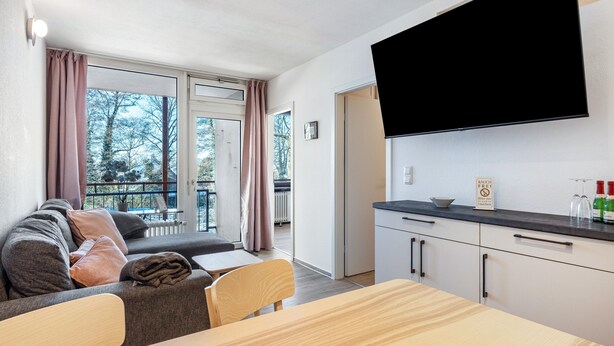 Una cocina moderna con televisor de pantalla plana, una mesa de comedor y un sofá con vistas al exterior.