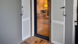 A room with a sliding door, a lamp, a chair, and a floor with patterned tiles. - Apartment 'The Pureness 1' with Shared Garden, Balcony and Wi-Fi (Hildesheim)