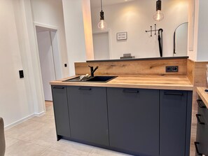 Une cuisine moderne avec un plan de travail en bois, des meubles noirs et des luminaires suspendus.
