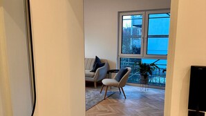 A modern interior with a herringbone floor, a sofa, a chair, and a potted plant. - Apartment 'The Pureness 1' with Shared Garden, Balcony and Wi-Fi (Hildesheim)