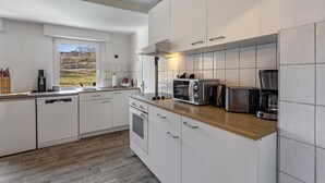 Eine moderne Küche mit weißen Schränken, einer Holz Arbeitsplatte, einem Einbauofen, einer Mikrowelle, einem Toaster und einer Kaffeemaschine.