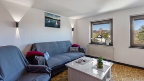 Ein Wohnzimmer mit einer Couch, einem Couchtisch, einem Gemälde und einem Fenster mit Blick.