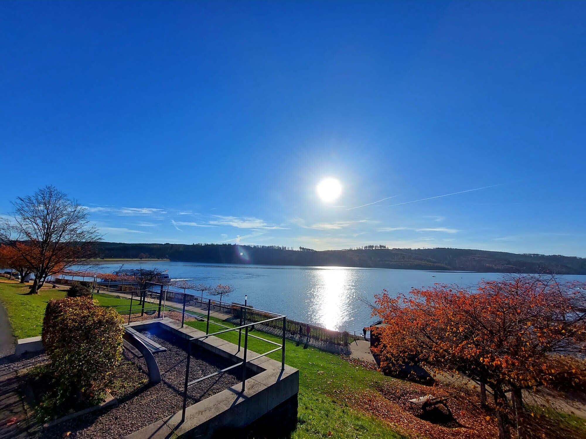 A lakeside view with a clear sky, a dock, and a well-maintained grassy area.