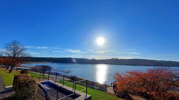 A lakeside view with a clear sky, a dock, and a well-maintained grassy area.
