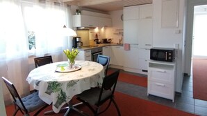 A compact kitchen with white cabinets, a microwave, and a dining area with a table and chairs. - Apartment '2' with Shared Garden and Wi-Fi (Meersburg)