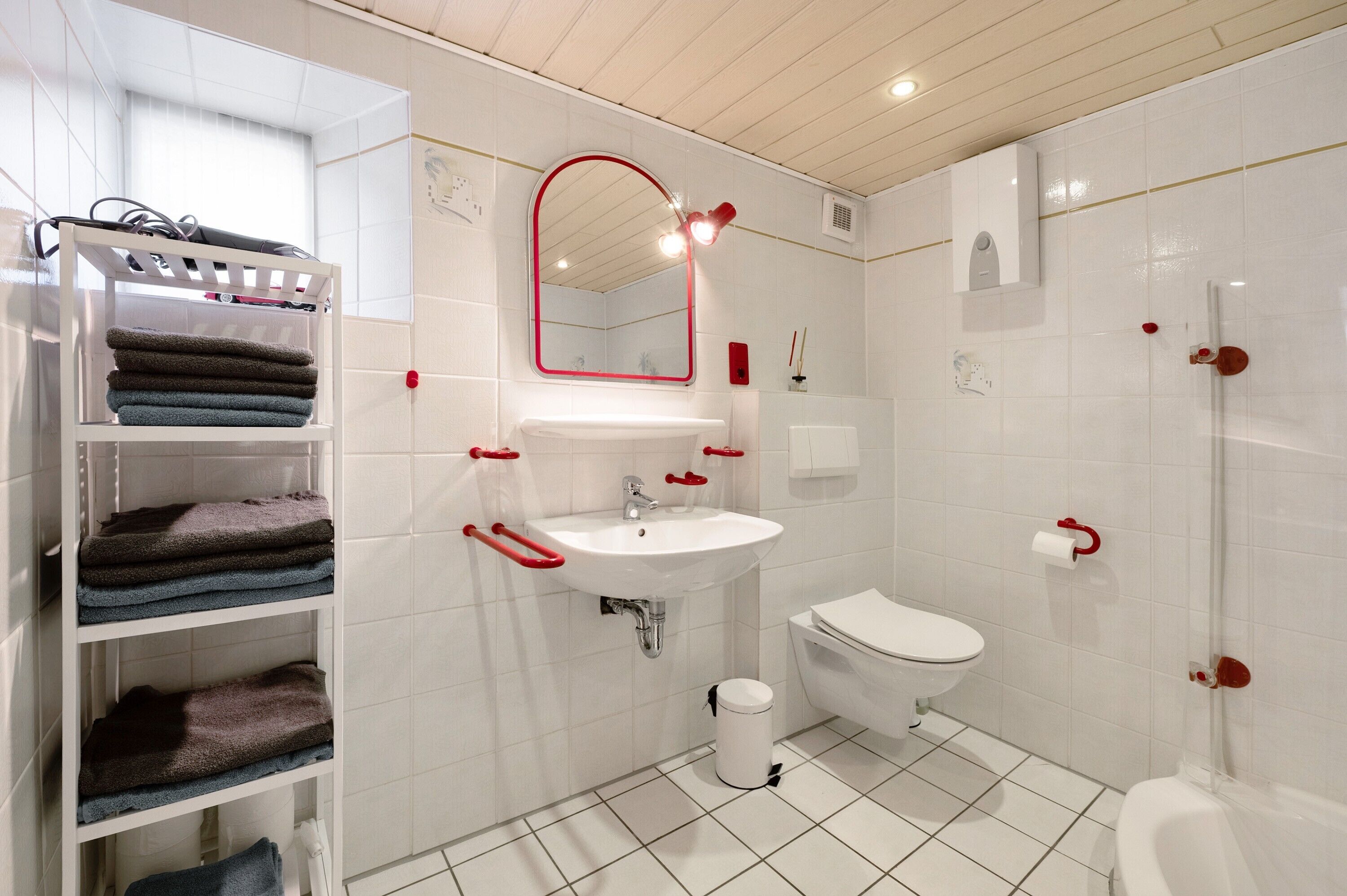 A bathroom with a white sink, a toilet, a shower, and a towel rack with towels.