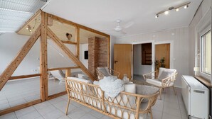 A room with a sloped ceiling, a white radiator, wicker furniture, and a wooden staircase. - Apartment 'Kaamter Ferkelsmarkt' with Wi-Fi (Zell an der Mosel)