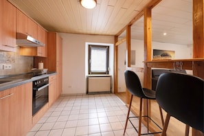 Una cocina con armarios de madera, una estufa y una ventana con persianas.
