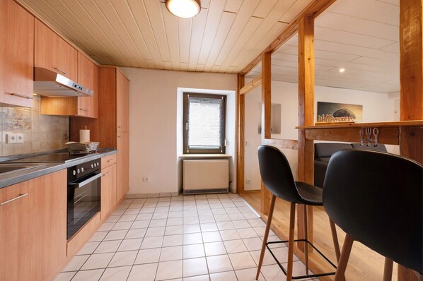 Una cocina con armarios de madera, una estufa y una ventana con persianas.