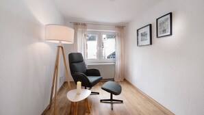 A room with a black chair, a small table with a candle, a floor lamp, and two framed pictures on the wall. - Apartment 'Kaamter Ferkelsmarkt' with Wi-Fi (Zell an der Mosel)