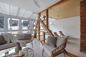 Un interior moderno con un techo alto, ventanas amplias y una escalera de madera.