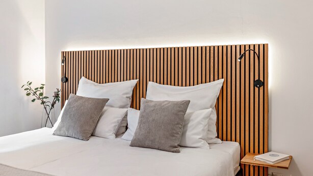 A modern bedroom with a wooden headboard, white bedding, and a bedside table with a book. - Vacation apartment "O" Black Forest - relaxation in a fantastic location (Münstertal/Schwarzwald)