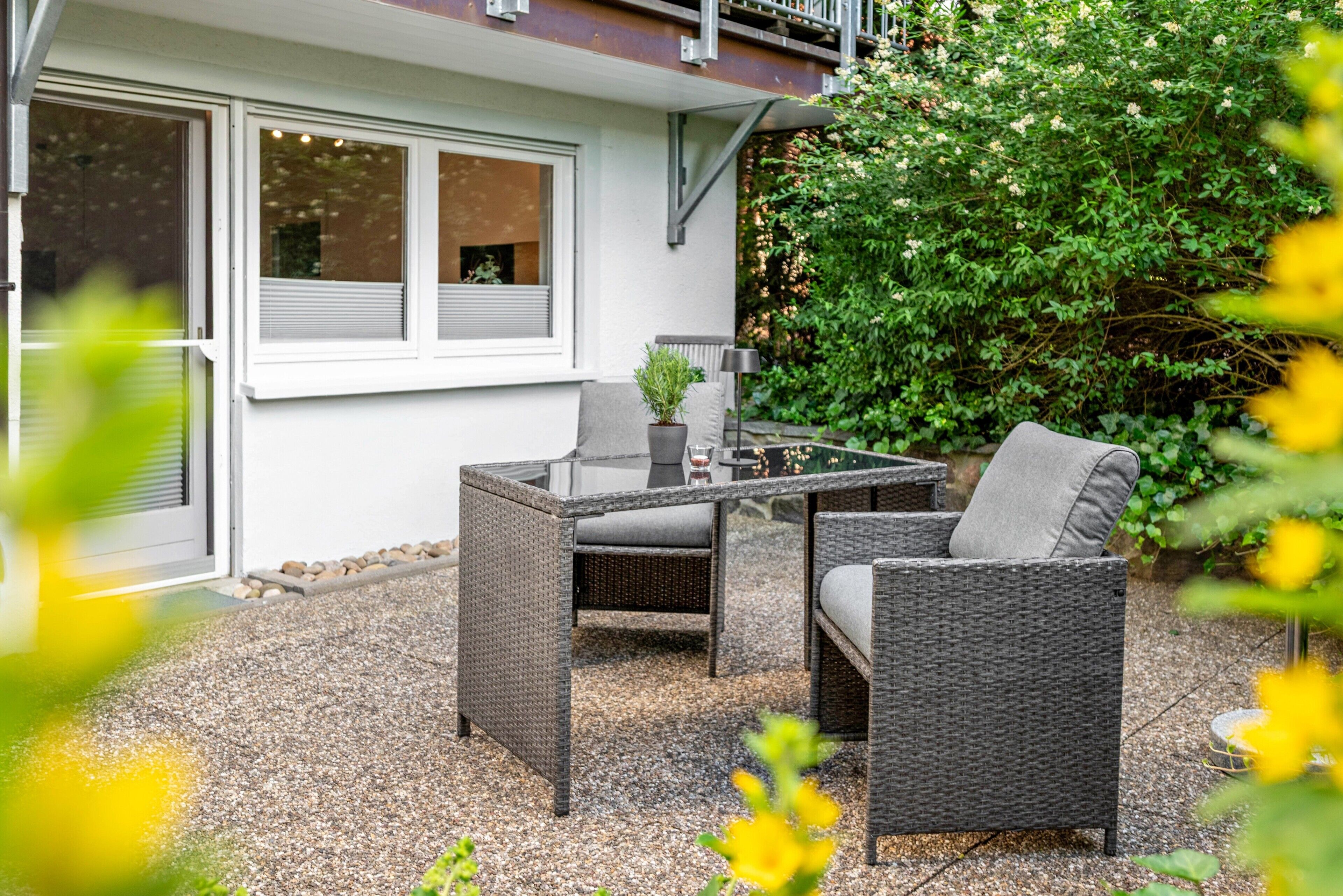 Eine Terrasse im Freien mit Korbmöbeln, einem Tisch und einem Blumentopf.