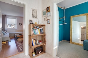 Une pièce avec une bibliothèque en bois, un miroir et une fenêtre avec des stores.