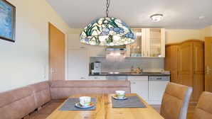 Ein Essbereich mit Holztisch, zwei Stühlen und einer Stukkdekorleuchte.