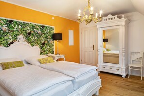 Une chambre avec deux lits, une armoire, un lustre et un miroir.