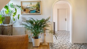 A hallway with a white door, a painting of a beach scene, and potted plants. - Holiday Apartment 'Veilchen' with Shared Garden, Balcony and Wi-Fi (Vogtsburg im Kaiserstuhl)