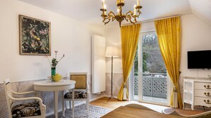A room with a chandelier, a table with chairs, a TV, and a window with curtains. - Holiday Apartment 'Veilchen' with Shared Garden, Balcony and Wi-Fi (Vogtsburg im Kaiserstuhl)