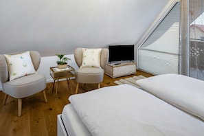 A bedroom with a bed, two chairs, a TV, a small table with a plant, and a window. - Studio 'Clematis' with Shared Garden, Balcony and Wi-Fi (Vogtsburg im Kaiserstuhl)