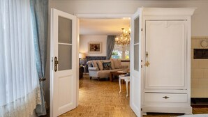 Una habitación con suelo de parqué de madera, un armario blanco, un sofá, una mesa y una lámpara.