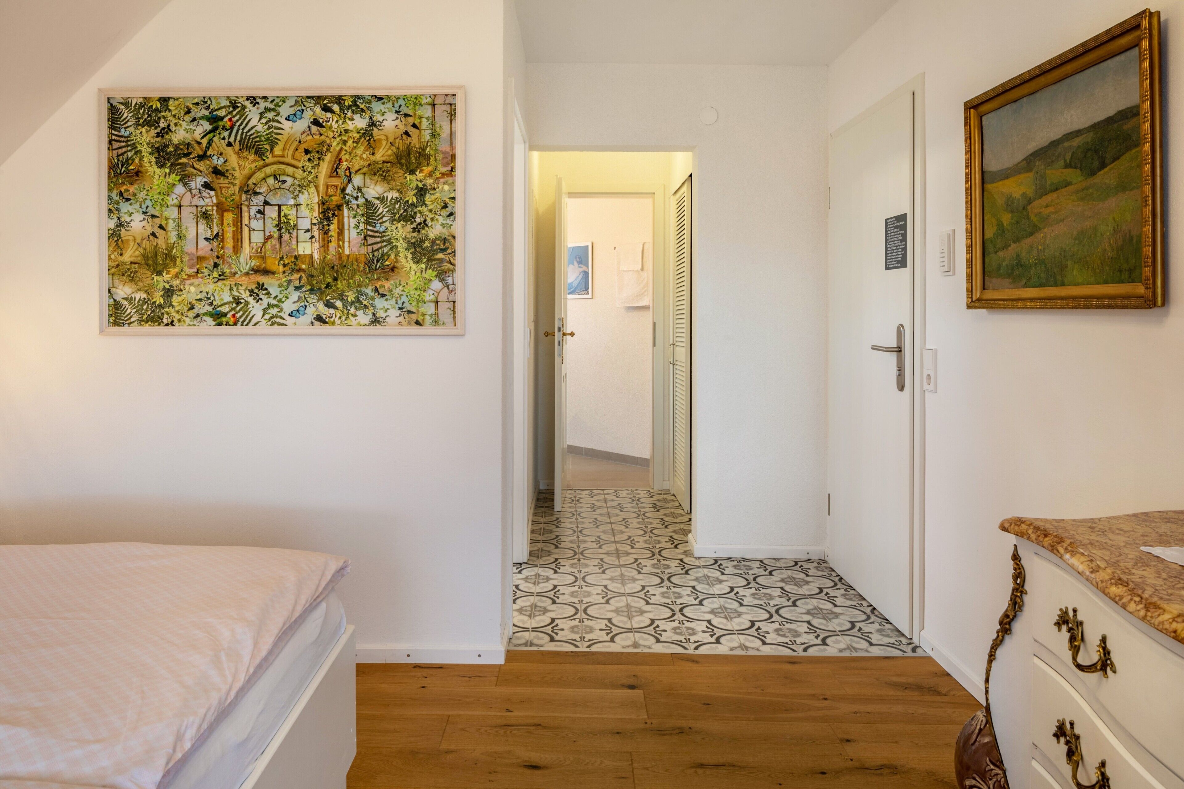 Une chambre avec un lit, un couloir menant à une salle de bain et un coin repas avec une table et des chaises.