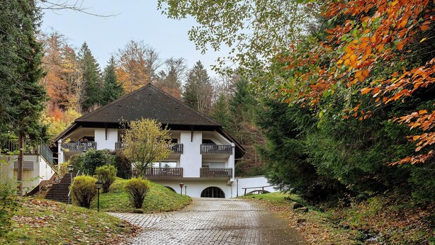 A building with a balcony, a paved pathway, and surrounding trees. - Apartment 'Bergblick' with Balcony and Wi-Fi (Triberg)