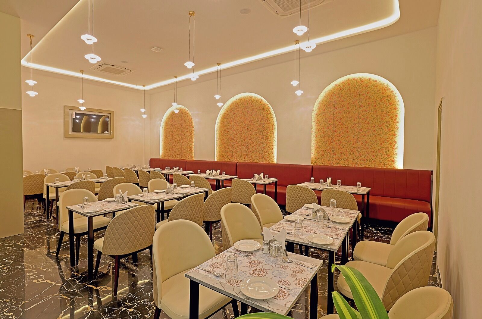 A restaurant with round tables, cushioned booths, and a marble floor.