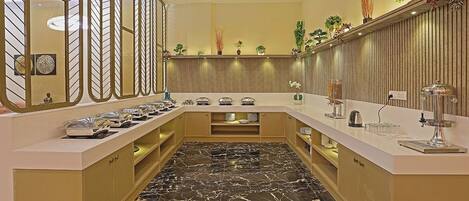A modern kitchen with marble flooring, stainless steel appliances, and a variety of plants and decorative items.