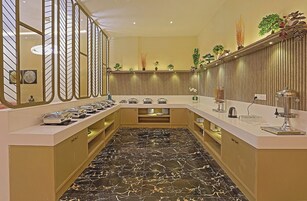 Una cocina moderna con suelo de mármol, electrodomésticos de acero inoxidable, plantas y objetos decorativos.