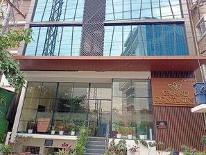A modern building with large windows, a sign reading 'Grand Continents,' and potted plants in front.