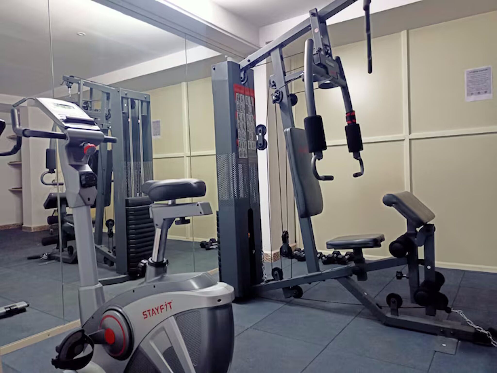 Ein Fitnessstudio mit verschiedenen Trainingsgeräten, darunter Laufbänder, Kraftgeräte und Bänke.