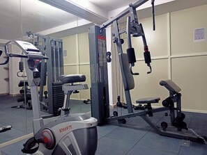 A gym with various exercise equipment, including a treadmill, weight machines, and benches.