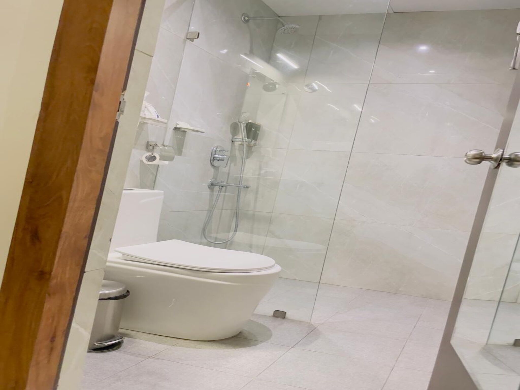 A modern bathroom with a glass-enclosed shower, a white toilet, and a tiled floor.
