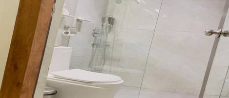 A modern bathroom with a glass-enclosed shower, a white toilet, and a tiled floor.