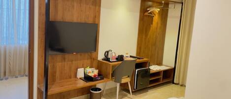 A hotel room with a wooden desk, a TV, a bed, and a wardrobe.