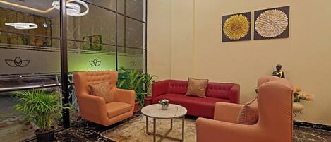 Un vestíbulo moderno con pared de vidrio, sofás rojos, sillones naranjas, suelo de mármol y decoración mural.