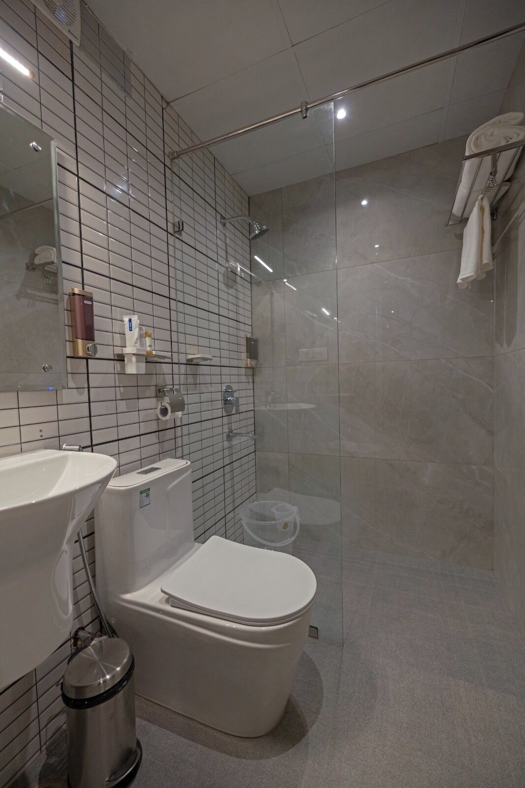 Un baño moderno con ducha de vidrio, lavamanos blanco y retrete.
