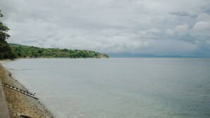 A coastal view with a clear sky, calm sea, and a distant shoreline with greenery and buildings.