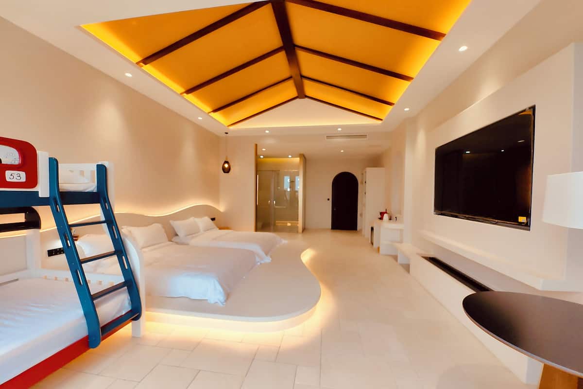 A modern hotel room with a bunk bed, a flat-screen TV, and a ceiling with a geometric design.