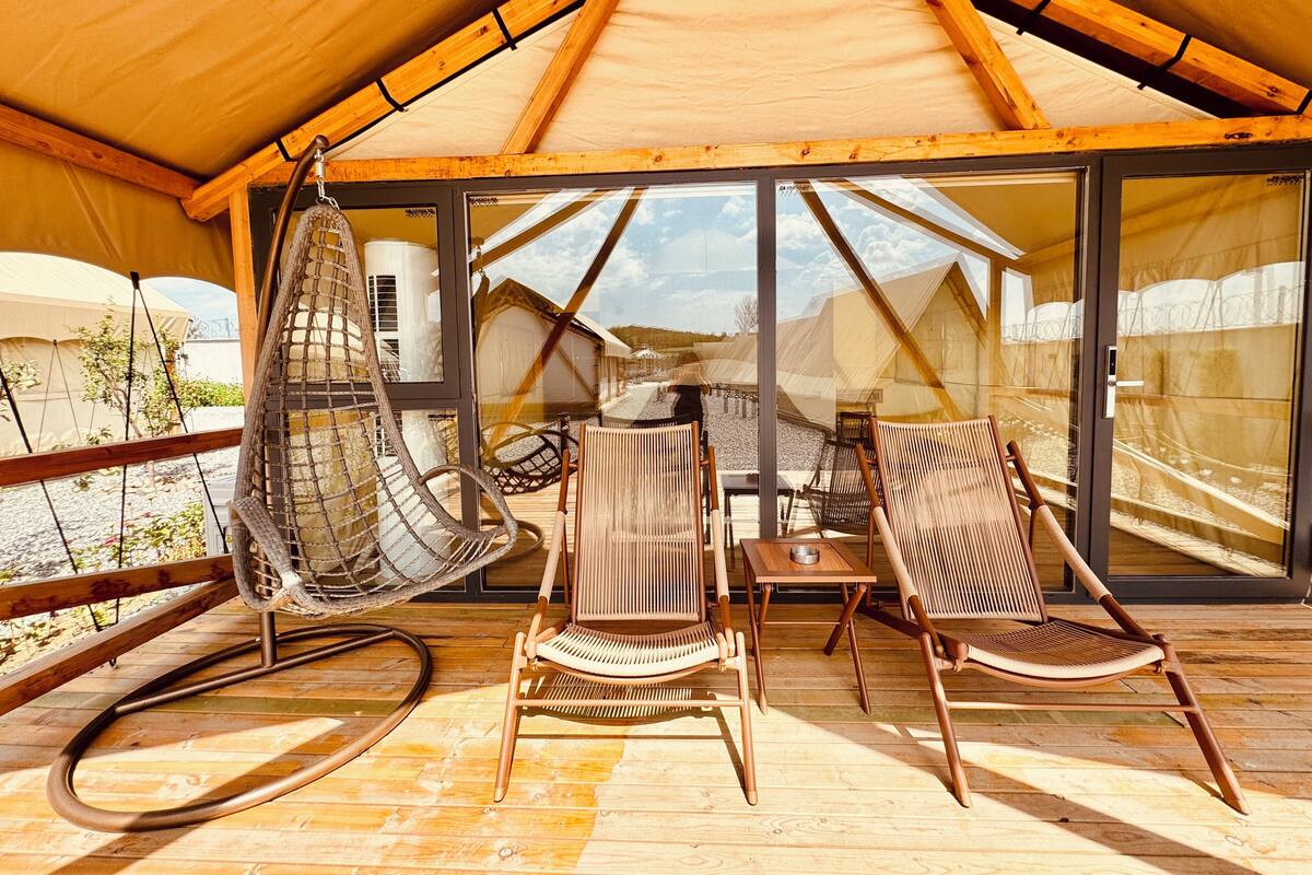 A cozy outdoor seating area with a hanging chair, two wicker chairs, and a small table.