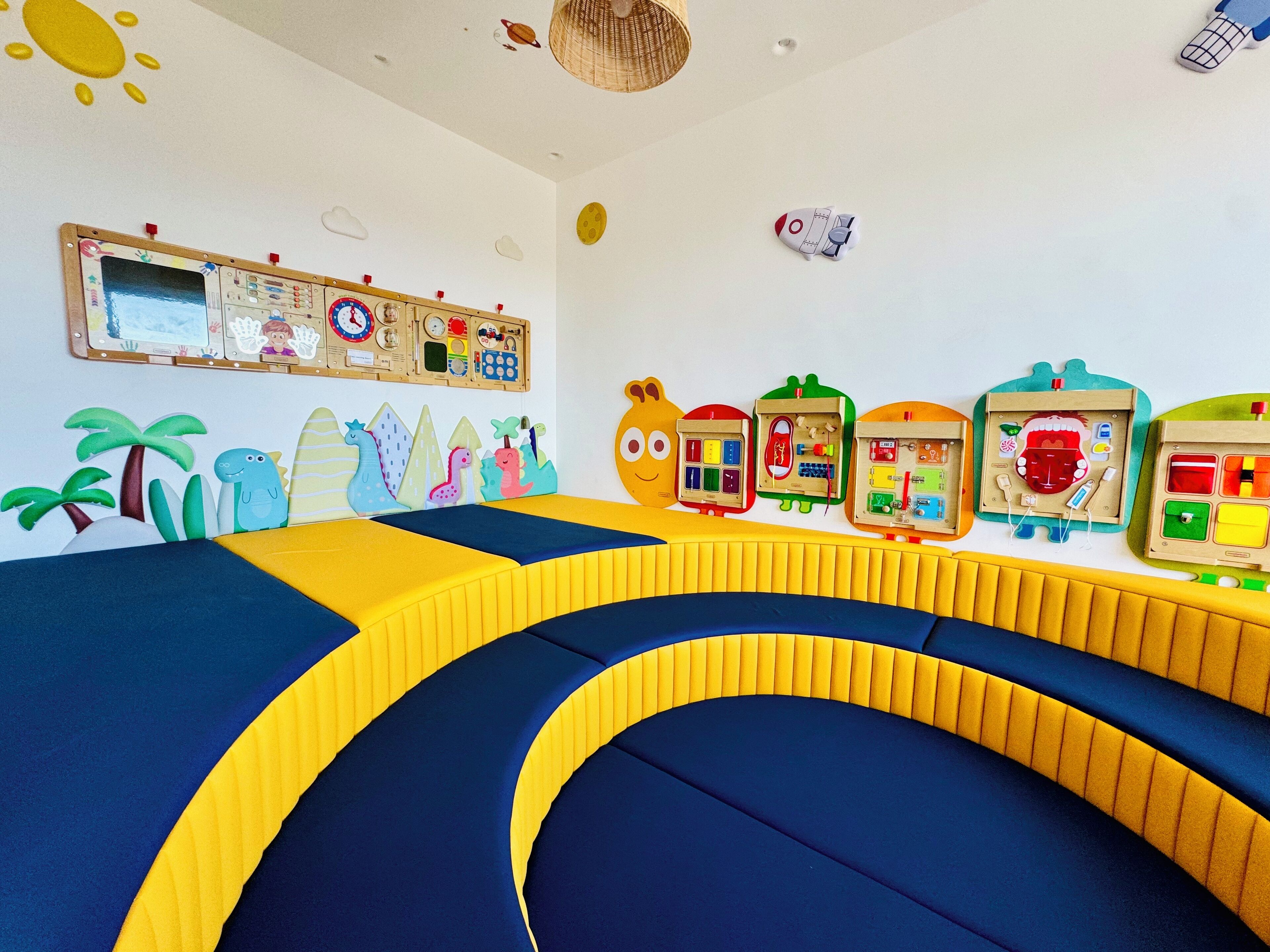 Zona de juegos infantiles con juguetes coloridos y un tapete de juego grande y curvo.