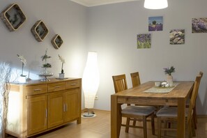 A dining area with a wooden table, chairs, and a cabinet. There are wall-mounted pictures and a lamp. - Ferienwohnung mit Terrasse, Bad Bodenteich (Bad Bodenteich)