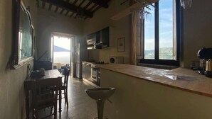 A kitchen with a large island, wooden chairs, and a view of the outdoors. - Luxury Retreat in Montevettolini (Montevettolini)
