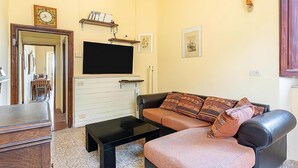 A living room with a sofa, a coffee table, a TV, a fireplace, and a bookshelf. - Luxury Retreat in Montevettolini (Montevettolini)