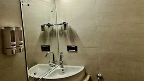 Ein Badezimmer mit Waschbecken, Spiegel und zwei Handtrocknern.