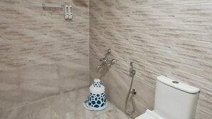 Ein Badezimmer mit Dusche, Toilette und einer Seifenspender an der Wand.